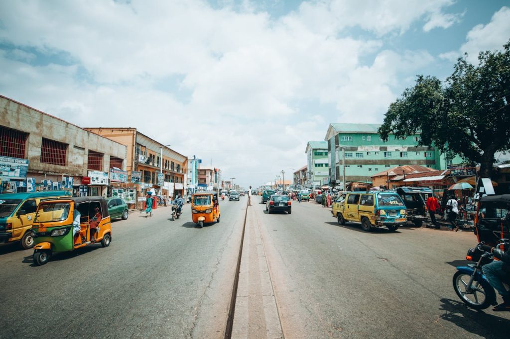 Bustling street scene in Kaduna, Nigeria, with colorful vehicles and lively activity.