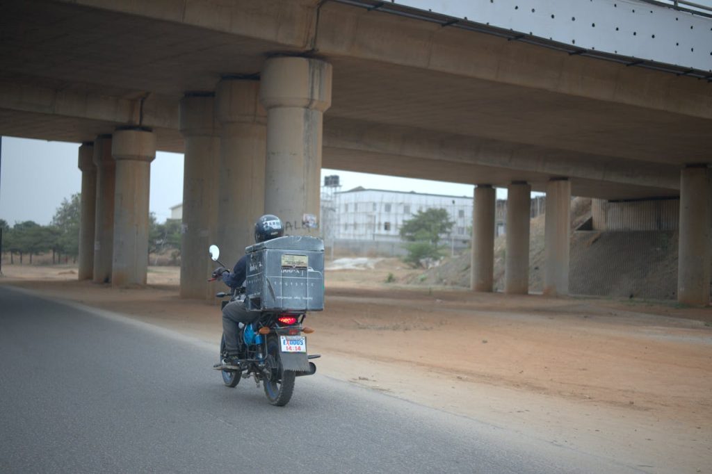 Motorcyclist riding under a highway bridge in Federal Capital Territory, Nigeria.